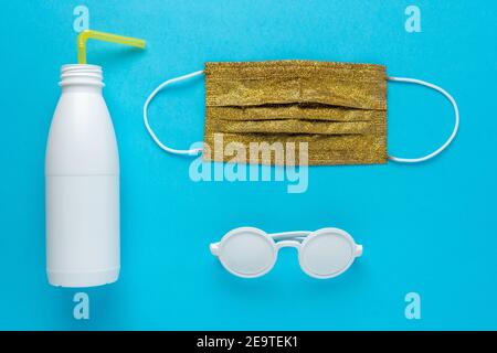 Plage d'été avec lunettes de soleil, bouteille blanche et masque médical. Épidémie minimale de coronavirus. Concept de verrouillage. Banque D'Images