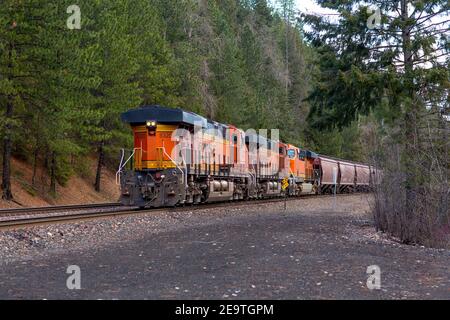 Trois locomotives tracées d'un train de marchandises à trémie couverte BNSF descendant les voies dans la ville de Troy, Montana. Burlington Nord et Banque D'Images