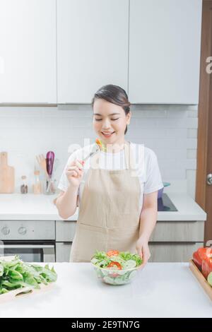 Pretty woman eating a salad dans la cuisine Banque D'Images