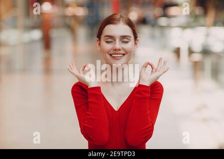 Portrait d'une jeune femme souriante avec les yeux fermés dans le centre commercial. Yoga, calme, zen et méditation concept à la pandemia covid-19. Banque D'Images