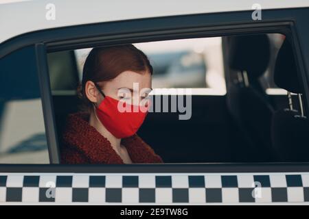 Une jeune femme passager prend un trajet en voiture de taxi pendant la quarantaine pandémique du coronavirus. Femme aux yeux fermés portant un masque médical stérile. Concept de la distance sociale et de la sécurité sanitaire dans les transports Banque D'Images