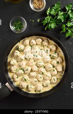 Boulettes de viande suédoises à la sauce blanche crémeuse dans une poêle sur fond de pierre noire. Vue de dessus, plan d'installation, gros plan Banque D'Images