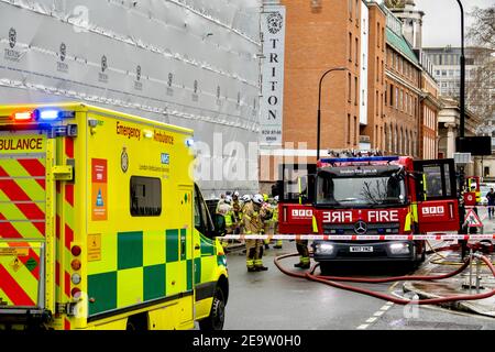 Une ambulance et un moteur d'incendie sur les lieux d'un incendie de maison d'incident majeur avec de multiples services d'urgence en présence. Un tuyau d'incendie repose sur le sol. Banque D'Images