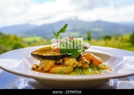 Une assiette de ceviche garnie d'herbes sur une table en face de la jungle. Costa Rica Banque D'Images