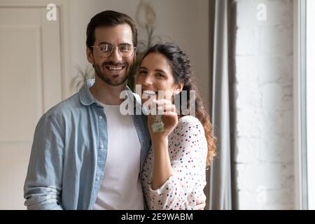 Portrait de propriétaires heureux de newlyweds regardant l'appareil photo montrant les clés Banque D'Images