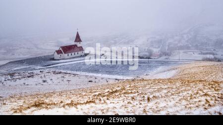 L'église de Vik i Myrdal au sommet de la colline pendant la neige épaisse au village de Vik en Islande en hiver. Banque D'Images
