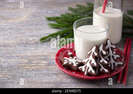 Biscuits de Noël faits maison au chocolat, décorés de glaçage, avec un verre de lait sur une table en bois, espace libre. Sélectif. Horizontal Banque D'Images