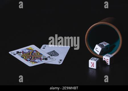 Cartes et une tasse de poker avec des dés isolés sur un arrière-plan noir Banque D'Images