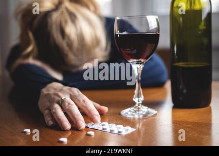 Femme après surdose de drogue et boire du vin rouge. Problèmes sociaux liés à la toxicomanie et à l'alcoolisme. Femme ivre seule à la maison. Concept d'alcoolisme Banque D'Images
