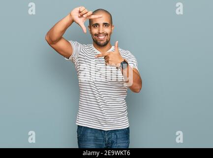 Hispanique adulte homme portant des vêtements décontractés souriant faisant cadre avec les mains et les doigts avec le visage heureux. Créativité et concept de photographie. Banque D'Images