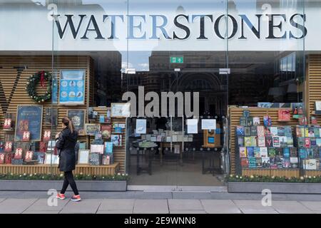 Une femme regarde dans la fenêtre de la branche de Victoria de la chaîne fermée de libraires, Waterstones lors du troisième confinement de la pandémie du coronavirus, le 5 février 2021, à Londres, en Angleterre. Le personnel a lancé une pétition appelant Waterstones à augmenter le salaire minimum des libraires à fourrure, après que les propriétaires de la chaîne, Elliott Advisors, ont récemment déposé des comptes, montrant que 107 employés du fonds de couverture de Londres ont été payés à 93,3 millions de livres sterling. Banque D'Images