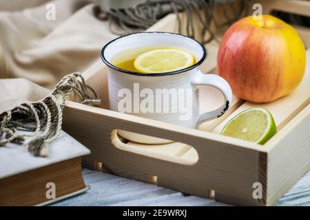 Thé chaud sur le plateau avec pomme et citron. Petit déjeuner ou rafraîchissement sain. Encore la vie avec le livre et le foulard sur la table Banque D'Images