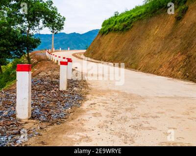 Superbe route de terre marquée de piquets rouges-blancs, grimpant les montagnes de Sapa, célèbre pour ses rizières en terrasse, nord du Vietnam Banque D'Images