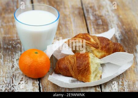 Petit déjeuner simple : croissant français, satsuma et verre de lait Banque D'Images