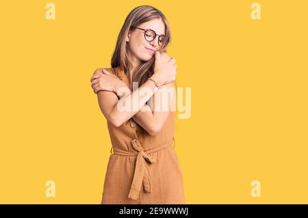 Jeune belle femme blonde portant des vêtements décontractés et des lunettes se embrassant heureux et positif, souriant confiant. Amour de soi et soin de soi Banque D'Images