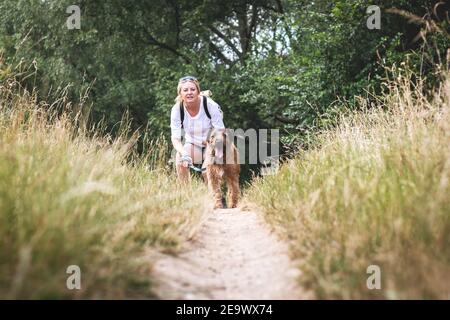 Femme avec son chien marchant à l'extérieur. Femme propriétaire d'animal de compagnie formant l'obéissance d'animal dans la nature à l'été Banque D'Images