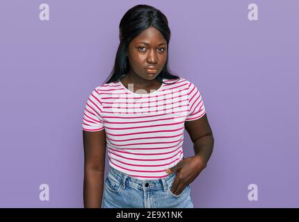 Jeune femme africaine portant un t-shirt rayé décontracté sceptique et nerveux, frowning contrarié à cause du problème. Personne négative. Banque D'Images