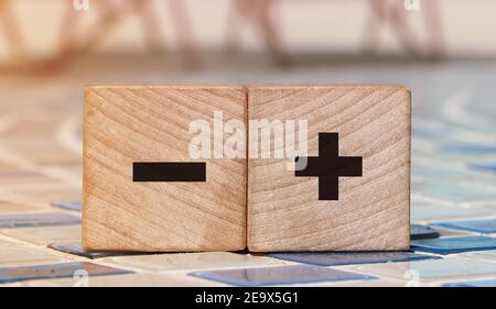 Signe plus et moins sur des cubes en bois sur un fond de plage détendu. Business Online concept. Banque D'Images