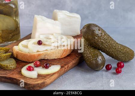 Des concombres marinés dans un pot en verre sur une planche de bois et un sandwich au bacon. Haricots moutarde en arrière-plan. Aliments fermentés. Copier l'espace. Banque D'Images