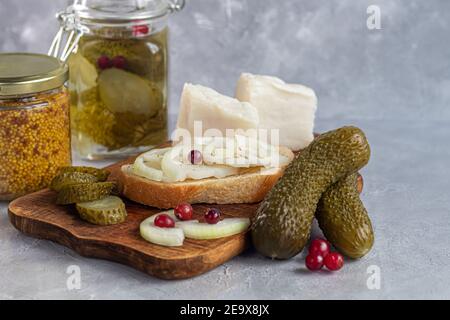 Des concombres marinés dans un pot en verre sur une planche de bois et un sandwich au bacon. Haricots moutarde en arrière-plan. Aliments fermentés. Copier l'espace. Banque D'Images