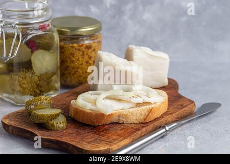 Des concombres marinés dans un pot en verre sur une planche de bois et un sandwich au bacon. Haricots moutarde en arrière-plan. Aliments fermentés. Copier l'espace. Banque D'Images