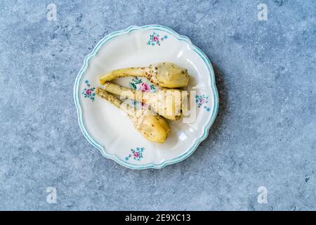 Coeurs d'artichaut épicés marinés à l'huile d'olive servis avec des racines. Prêt à manger. Banque D'Images