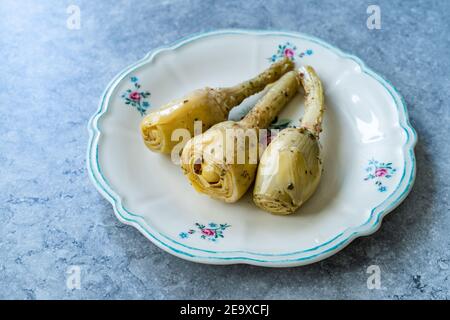 Coeurs d'artichaut épicés marinés à l'huile d'olive servis avec des racines. Prêt à manger. Banque D'Images