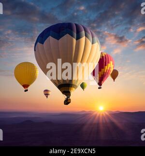 Des ballons d'air chaud survollent au lever du soleil au-dessus des sommets de la Cappadoce. Banque D'Images