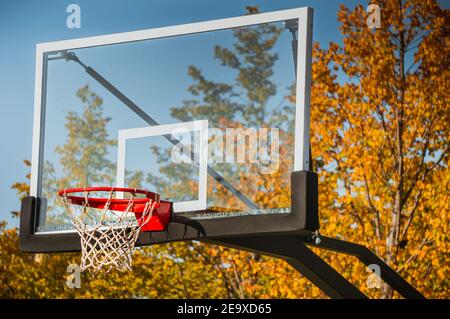 Panier de basket-ball avec filet et planche transparente dans le parc d'automne avec ciel bleu Banque D'Images