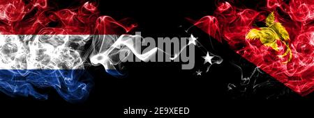 Les pays-Bas contre la Papouasie-Nouvelle-Guinée ont fumé des drapeaux mystiques placés côte à côte. Drapeaux de fumée abstraits épais de couleur soyeuse. Banque D'Images