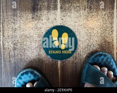 Tenez-vous debout ici, panneau ou symbole de pied sur le sol, style de vue de dessus Banque D'Images