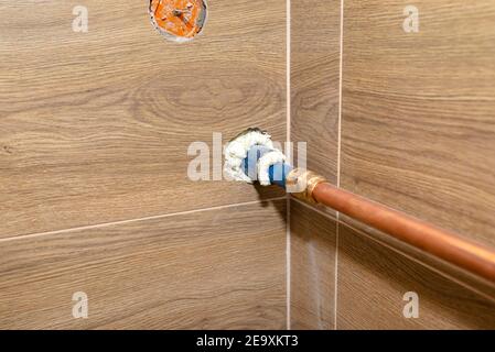 Tuyau en cuivre pour les installations au gaz naturel, venant du mur à la chaufferie bordée de carreaux de céramique. Banque D'Images