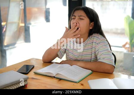 fille asiatique étudiant bâillant en lisant le livre se sentant fatigué s'ennuyer endormi. éducation des enfants Banque D'Images