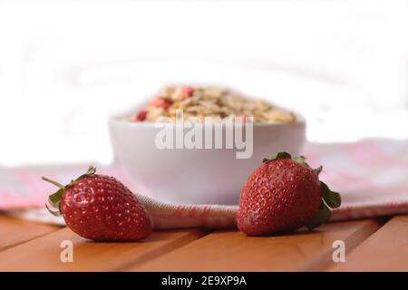 fraises et un bol de muesli sur une serviette sur une table en bois isolée sur fond blanc. Concept de saine alimentation. L'image contient de l'espace de copie Banque D'Images