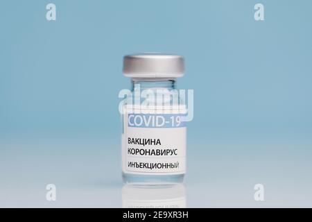 Flacon en verre contenant le vaccin COVID 19 placé sur la table sur fond bleu Banque D'Images
