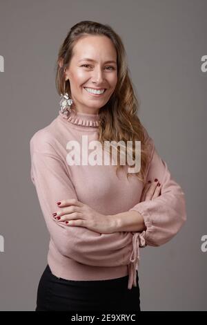 Portrait d'une femme d'affaires élégante et heureuse debout avec les bras croisés en studio regardant l'appareil photo Banque D'Images