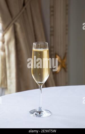 Verre de vin mousseux en cristal servi sur une table ronde blanche dans un restaurant élégant à la lumière du jour Banque D'Images
