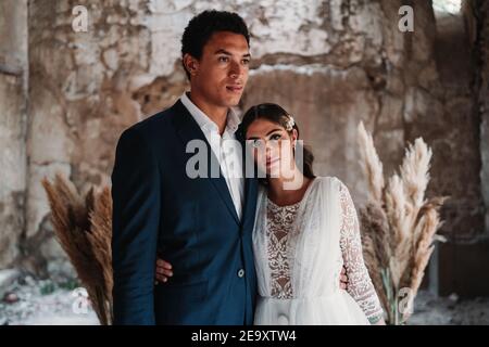 Un jeune couple épris de jeunes jeunes mariés de souche portant des vêtements de mariage chics embrassant doucement dans le bâtiment obsolète restant Banque D'Images