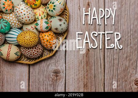 Joyeux Pâques texte carte de message.coloré peint à la main décoré oeufs de Pâques Et ruban.oeufs de Pâques faits à la main sur table en bois.décoration de printemps Banque D'Images