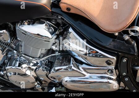 Moto moderne et puissante avec surface moteur brillante et réfléchissante en chrome et tuyaux d'échappement dans le parking de la rue, vue rapprochée. Banque D'Images