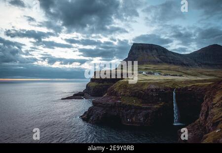 Le village de Gasadalur et Mulafossur sa chute d'eau emblématique au coucher du soleil en été avec le ciel bleu. Gélose, Îles Féroé, Danemark. La plus grossière dans le nord Banque D'Images