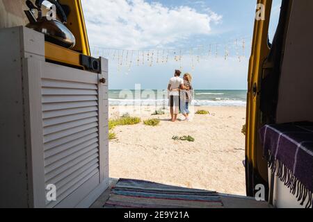 Jeune couple d'Europe de l'est voyageant en minibus jaune de camping le long de la mer et de se détendre à la plage. Auto-construit hors-réseau camping camping-car i Banque D'Images