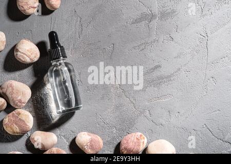 Soin de la peau essence compte-gouttes d'huile dans un flacon en verre près de galets Banque D'Images