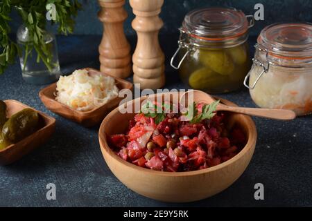 Vinegret ou vinaigrette. Salade rouge russe traditionnelle avec légumes cuits et marinés, petits pois, betteraves, dans un bol en bois sur fond rustique. Banque D'Images