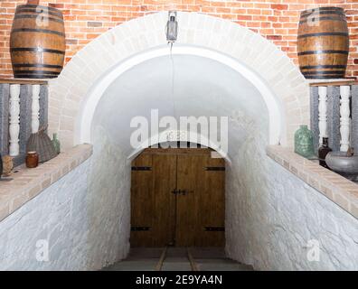 Entrée principale d'une ancienne cave moldave. Sur l'image se trouvent des murs blancs et une porte en bois. Banque D'Images