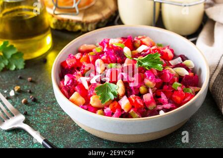 Vinaigrette de salade de betteraves en gros plan avec concombre mariné, haricots, carottes, petits pois, choucroute sur un comptoir foncé. Banque D'Images