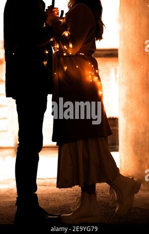 silhouettes de deux personnes - un gars et une fille, mari et femme, attaché avec une guirlande avec des lumières Banque D'Images