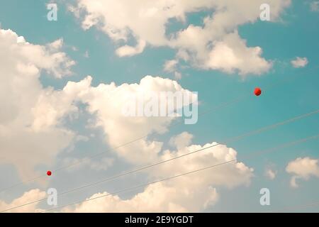 fils avec ballons rouges, nuages d'air blanc contre le ciel bleu. clair chaud jour d'été Banque D'Images