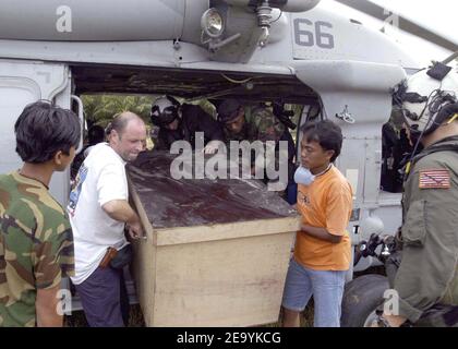 Les travailleurs de l'aide étrangère et le personnel militaire travaillent ensemble pour décharger une boîte de fournitures de secours d'un hélicoptère MH-60S Knighthawk affecté au Eleven (HC-11) de l'escadron de soutien au combat des hélicoptères -Gunbearers- of Helicopter. Des hélicoptères affectés à la deuxième Escadre aérienne Carrier (CVW-2) et des marins d'Abraham Lincoln soutiennent l'opération Unified assistance, l'opération humanitaire à la suite du tsunami qui a frappé l'Asie du Sud-est. Photo de Patrick M. Bonafede/USN via ABACA Banque D'Images