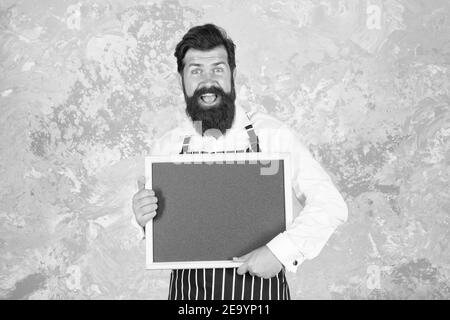 publicité de votre produit. hipster cook ou barista présentant le produit. sentez le succès. menu du café. cuisine ravie. cuisine du chef de restaurant. barbu brutal avec tableau noir. Banque D'Images